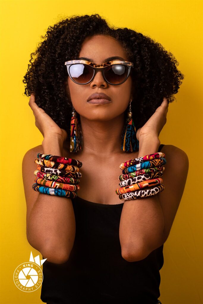 Pretty woman with shades and African bangles and earrings.